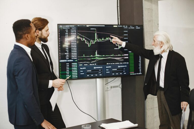 A diverse business team in a meeting analyzing stock market data on a screen.